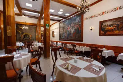 a restaurant with white tables and chairs and a painting on the wall at Hotel Hacienda Cusco Plaza in Cusco