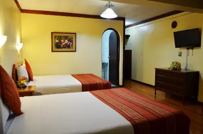 a hotel room with two beds and a tv at Nodo Cusco Santa Teresa in Cusco