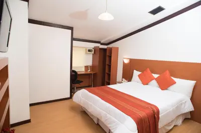 a hotel room with a bed with orange pillows at Nodo Cusco Santa Teresa in Cusco