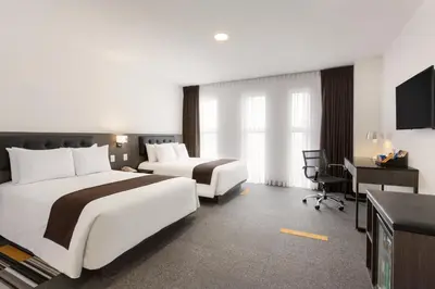 a hotel room with two beds and a desk at Wyndham Costa del Sol Lima Airport in Lima