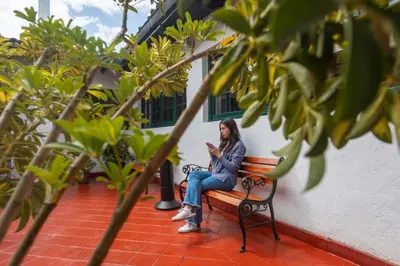 a woman sitting on a bench looking at her cell phone at Casa Andina Standard Cusco Catedral in Cusco