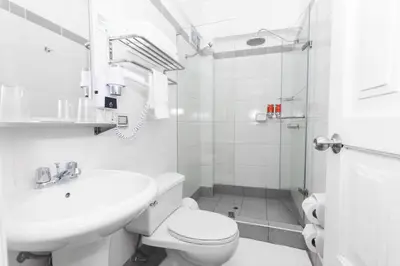 a white bathroom with a toilet and a sink at Casa Andina Standard Cusco Catedral in Cusco