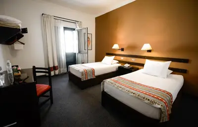 a hotel room with two beds and a window at Hotel Raymi in Cusco