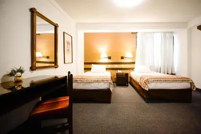 a hotel room with two beds and a mirror at Hotel Raymi in Cusco