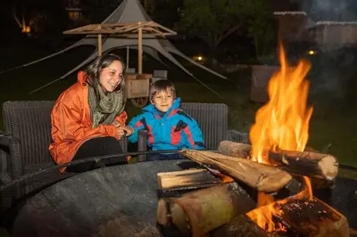 a woman and a child sitting next to a fire at Casa Andina Premium Valle Sagrado Hotel & Villas in Urubamba