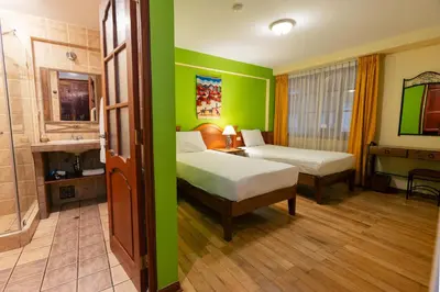 a hotel room with two beds and a bathroom at Amerindia in Cusco
