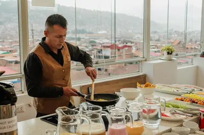 a man cooking in a pan in a kitchen at Cozy Room Cusco in Cusco