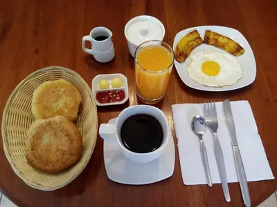 a table with a plate of breakfast food and a cup of coffee at Maudi Lodging in La Merced