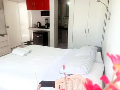 a bedroom with a white bed and a kitchen at Monterrico Suites Hotel in Lima