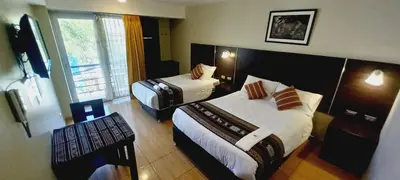a hotel room with two beds and a window at Hotel Mantas Cusco in Cusco