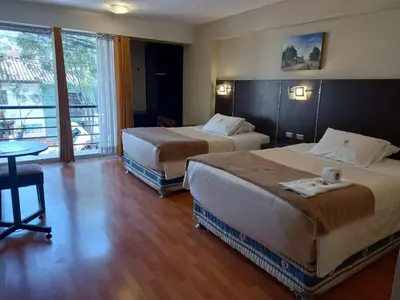 a hotel room with two beds and a table at Hotel Mantas Cusco in Cusco