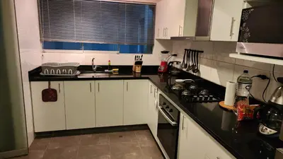 a kitchen with white cabinets and a black counter top at Miraflores Modern Baja Balta in Lima