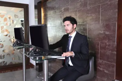 a man in a suit sitting at a desk with a computer at Hotel Rivera Inn in Lima