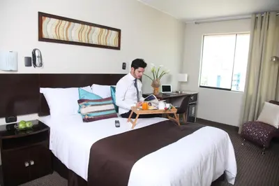 a man sitting at a desk in a hotel room at Hotel Rivera Inn in Lima
