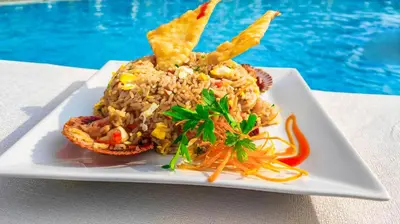a plate of food on a table next to a pool at Resort la Fogata Cieneguilla in Cieneguilla