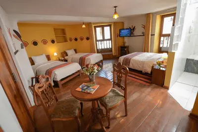 a hotel room with two beds and a table and chairs at Eureka San Blas in Cusco