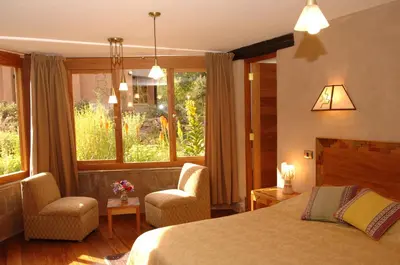 a hotel room with a bed and a chair and windows at Willka T'ika in Urubamba