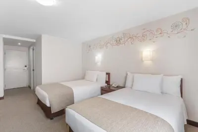 two beds in a hotel room with white walls at Wyndham Costa del Sol Cusco in Cusco