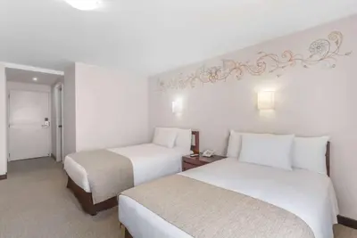 two beds in a hotel room with white walls at Wyndham Costa del Sol Cusco in Cusco