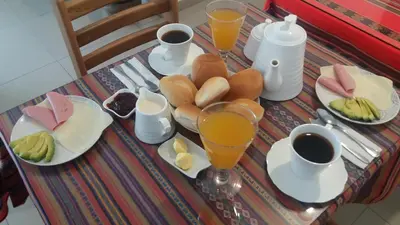a table with plates of food and glasses of orange juice at La Maison de Lydia in Nazca