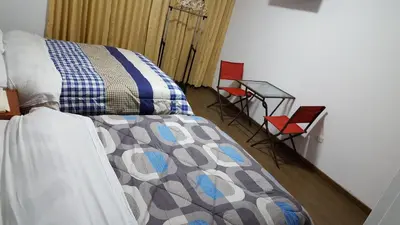 a bedroom with a bed and two red chairs at Hotel Shelter in Huancayo