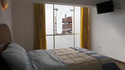a bedroom with a bed and a large window at Hotel Shelter in Huancayo