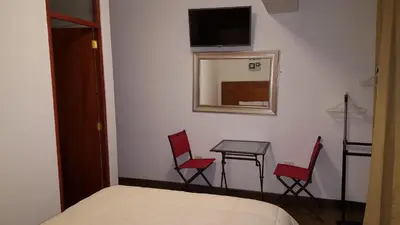 a bedroom with a bed and two chairs and a table at Hotel Shelter in Huancayo