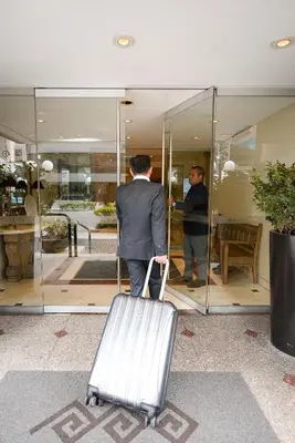 a man in a suit with a suitcase in front of a building at Los Tallanes Hotel & Suites in Lima