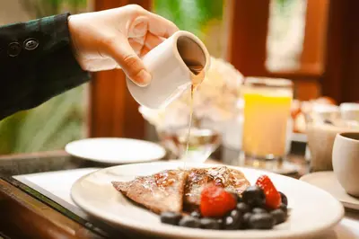 a person pouring syrup onto a plate of food at Los Tallanes Hotel & Suites in Lima