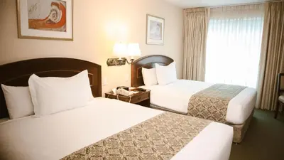 a hotel room with two beds and a window at Los Tallanes Hotel & Suites in Lima