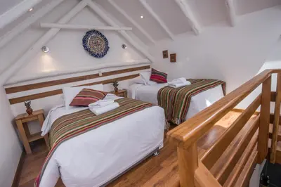 two beds in a room with a staircase at Casa Cavassa Centro Histórico Cusco in Cusco