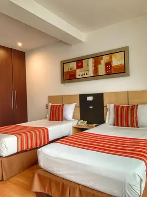 a hotel room with two beds with red and white sheets at Allpa Hotel & Suites in Lima