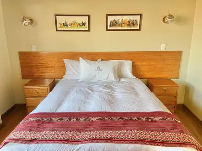 a bedroom with a large bed with a wooden headboard at Hostal Casona Arrambide in Cusco
