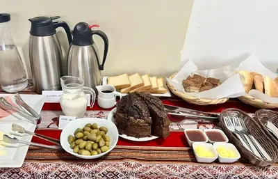 a table with a plate of food and bread and milk at Hostal Casona Arrambide in Cusco