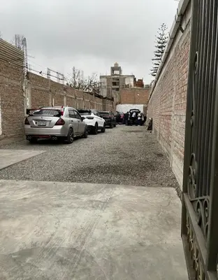 a parking lot with cars parked next to a brick wall at El Huerto Hostel in Ica