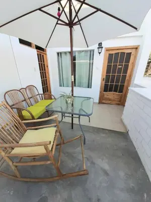 a patio with chairs and a glass table and an umbrella at El Huerto Hostel in Ica