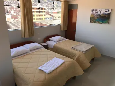 a hotel room with two beds and a window at Edmoli Casa Hospedaje in Cusco