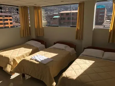 two beds in a room with two windows at Edmoli Casa Hospedaje in Cusco