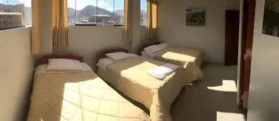 a room with three beds and a window at Edmoli Casa Hospedaje in Cusco