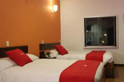 two beds in a room with red pillows on them at Hotel Limacpampa in Cusco