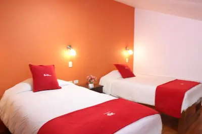 two beds in a room with red and white at Hotel Limacpampa in Cusco