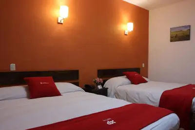 a hotel room with two beds with red pillows at Hotel Limacpampa in Cusco