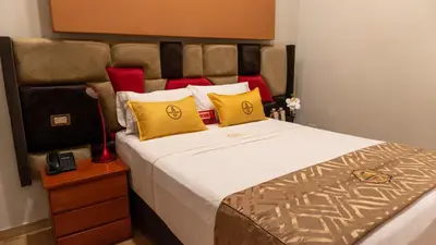 a bedroom with a large bed with yellow and red pillows at Montreal Magdalena Del Mar Hotel in Lima