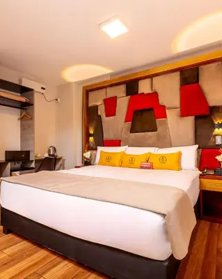 a bedroom with a large bed with yellow and red pillows at Montreal Magdalena Del Mar Hotel in Lima