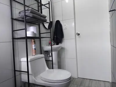a bathroom with a toilet and a shelf with towels at Studio in historic center Cusco in Cusco