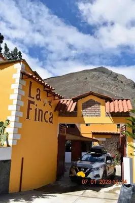 a yellow building with a car parked in front of it at La Finca Tarma in Tarma