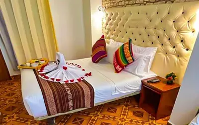 a bedroom with a bed with a headboard and a table at Hotel Machupicchu Adventure in Machu Picchu