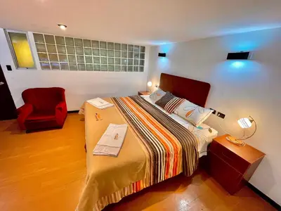 a hotel room with a bed and a red chair at Mama's House in Cusco