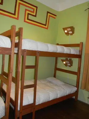 two bunk beds in a room with a green wall at Pirwa Backpackers Colonial in Cusco