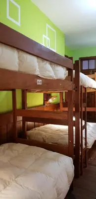 three bunk beds in a room with a green wall at Pirwa Backpackers Colonial in Cusco